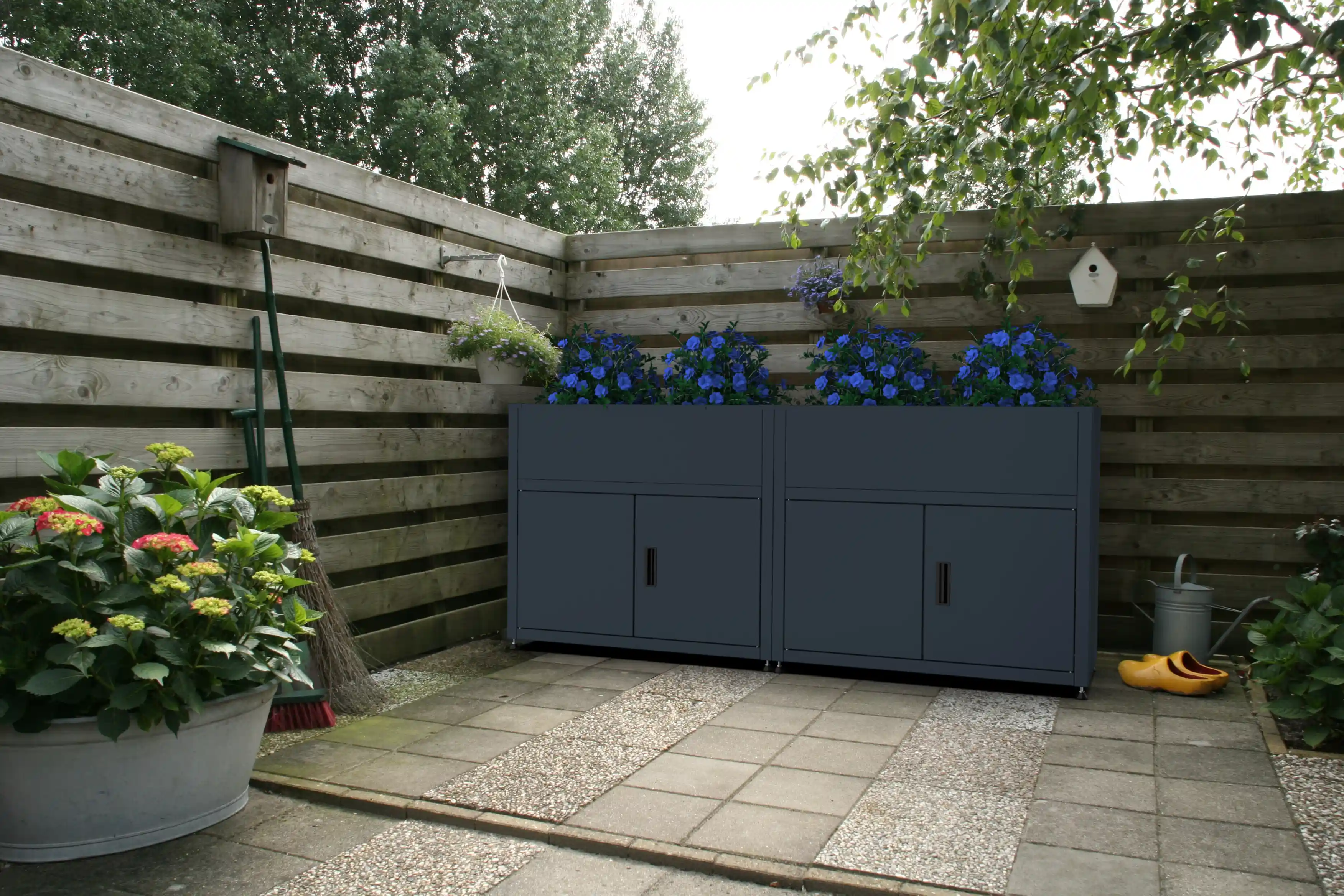 Zwei Pflanzkästen mit Unterschrank nebeneinander als lange Pflanzreihe im Garten aufgestellt.